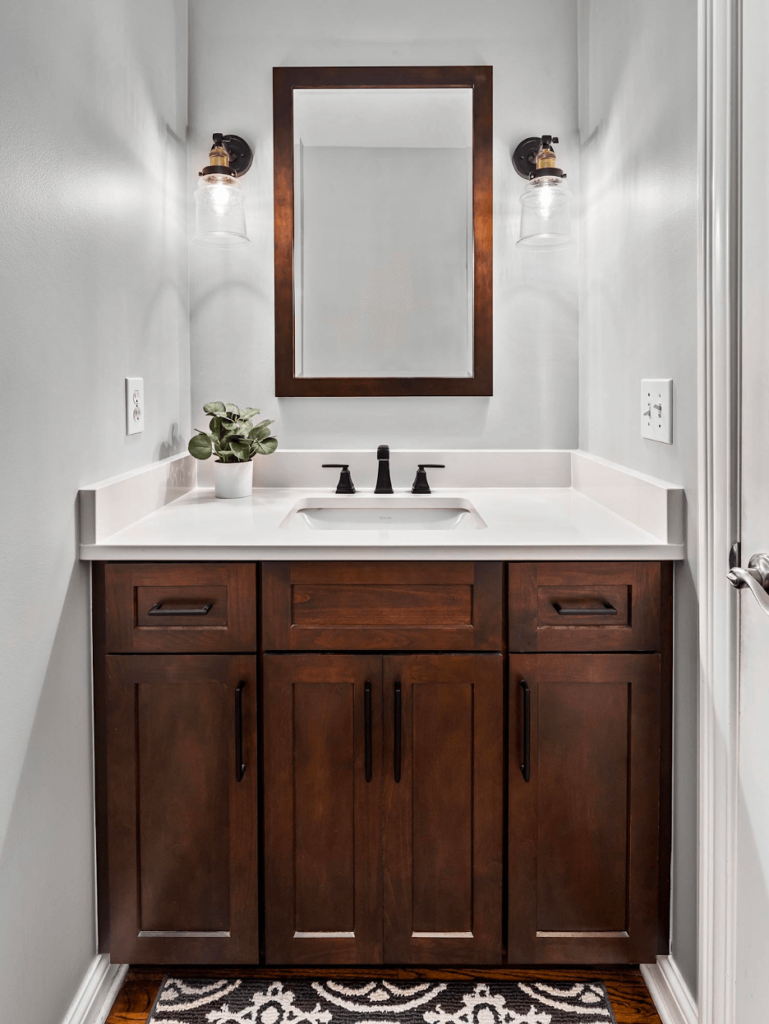 A close-up of a bathroom vanity in a deep wood shade with a white countertop.
